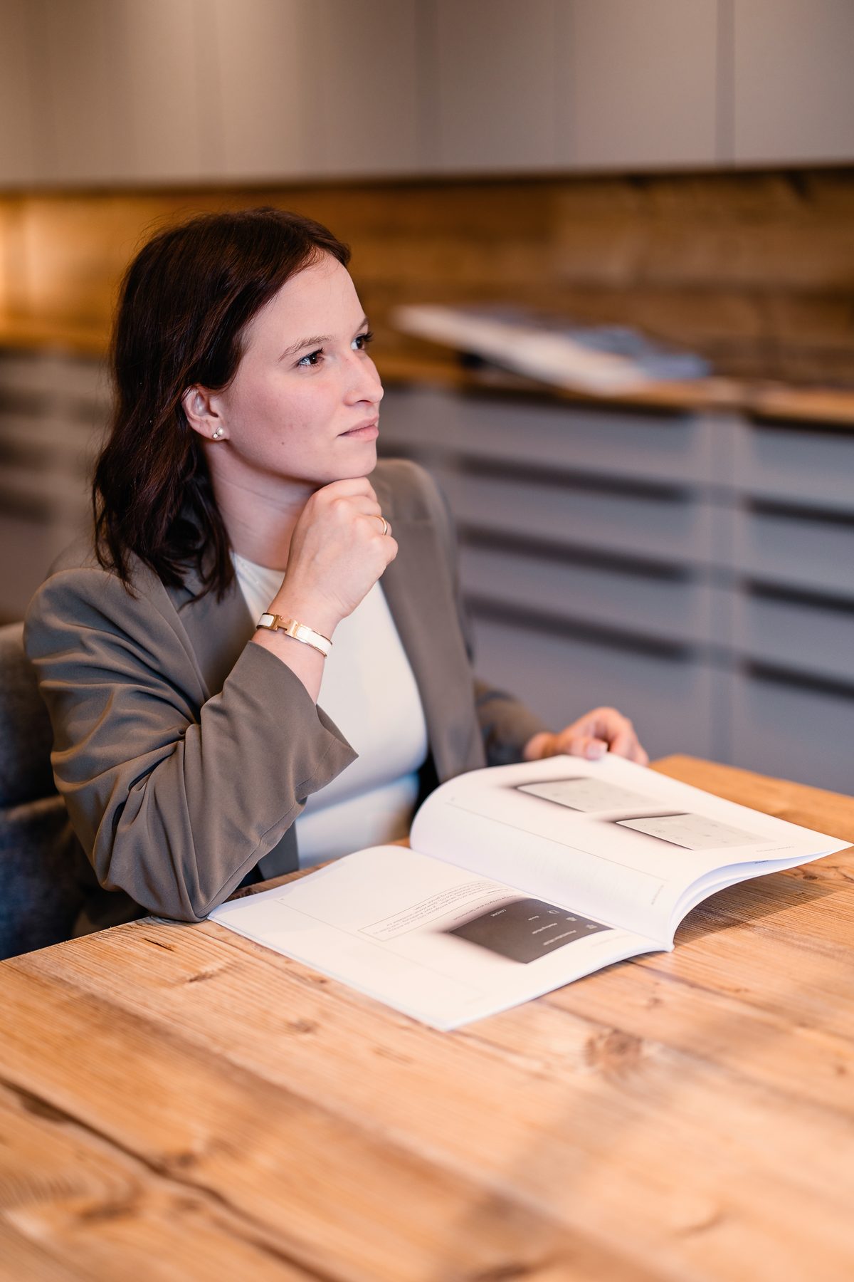 Laura plant am Tisch mit einem Katalog